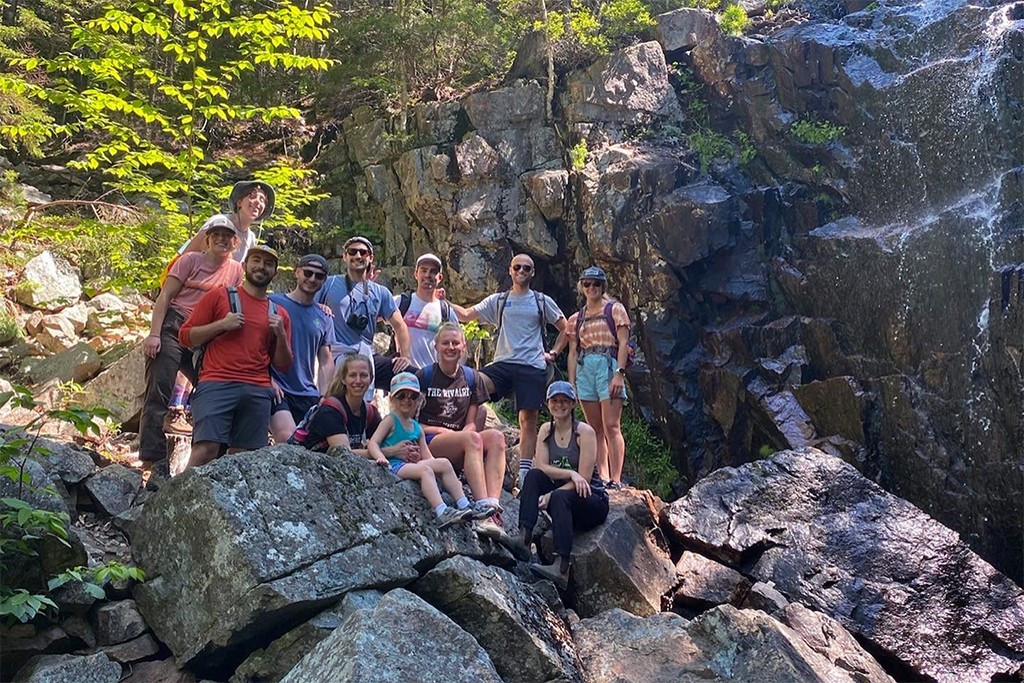 A group of U N E students standing on rocks during a hiking trip