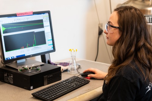 A student sits in front of a computer monitor that displays graphical data from a chemistry experiment