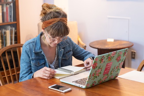 A student looks through their notes, a laptop is open in front of them