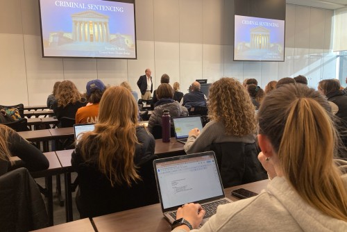 Several students in a lecture on Criminal Sentencing, focused on their laptops, engaged in a learning activity together