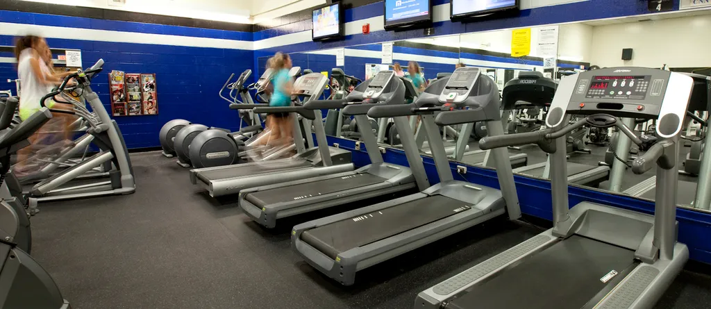 a row of treadills in the university fitness center with a student running on one