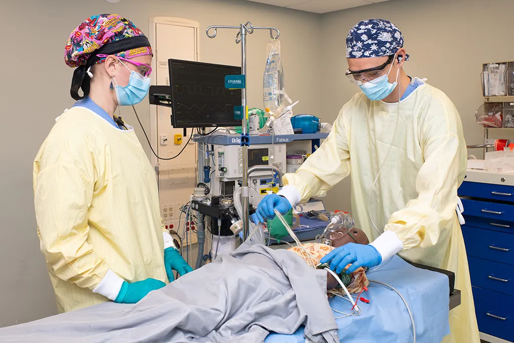 Two U N E D N P students practice on a patient simulator