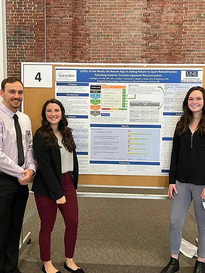 Jonathan Lindau, Cassidy Sirois, and Taylor Lockwood stand in front of a poster they presented