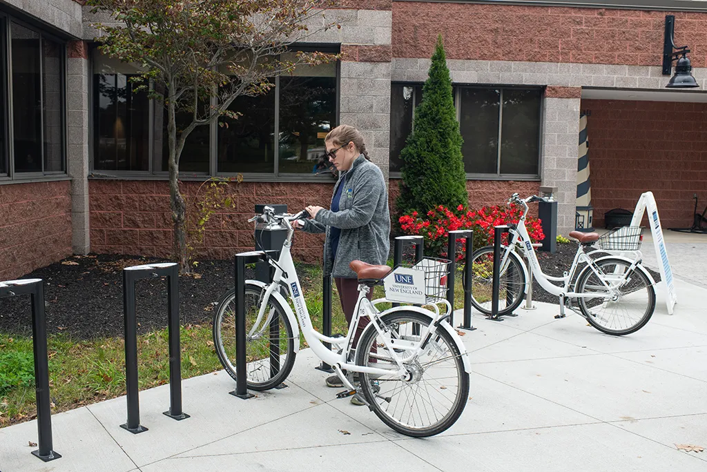 A U N E student getting a bike from the U N E bike share rack