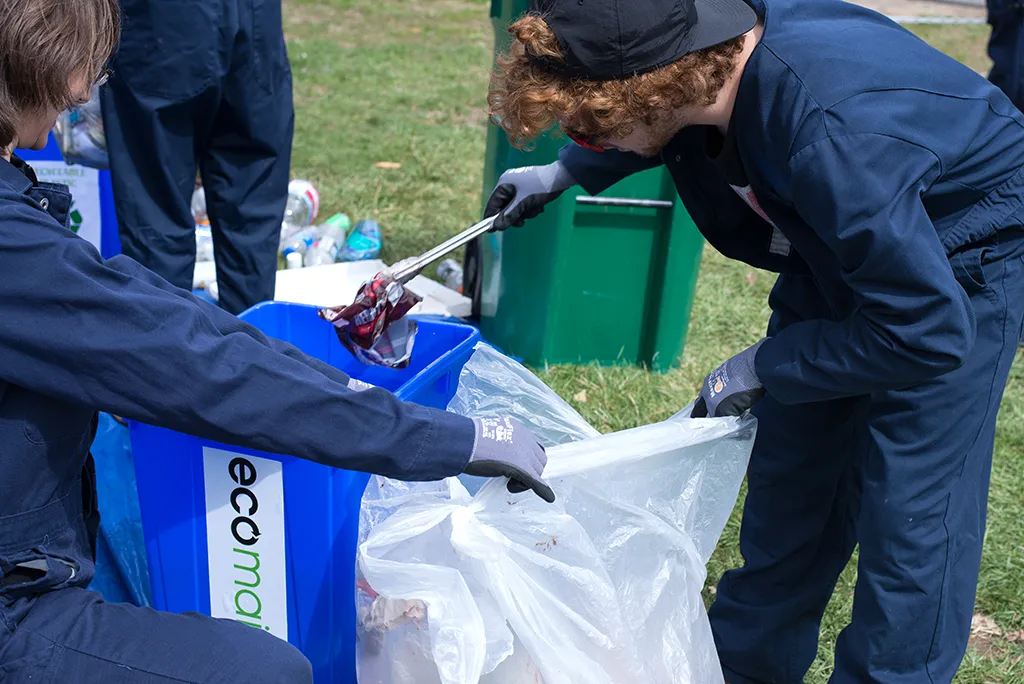 Two students sort through a trash bag to look for items that can be recycled