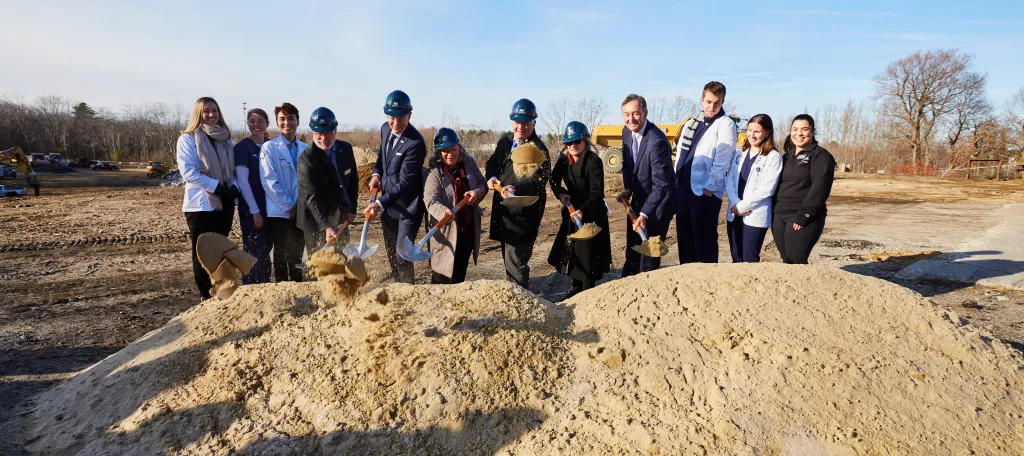 UNE leadership dig into the earth at the groundbreaking ceremony for the Harold and Bibby Center for Health Sciences on Tuesday, Nov. 29, 2022