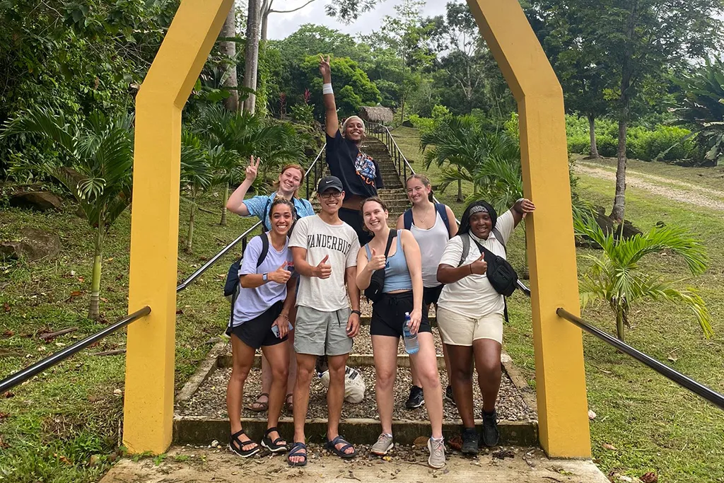 Ana Maria Castellanos and others stand in front of a yellow entrance gate