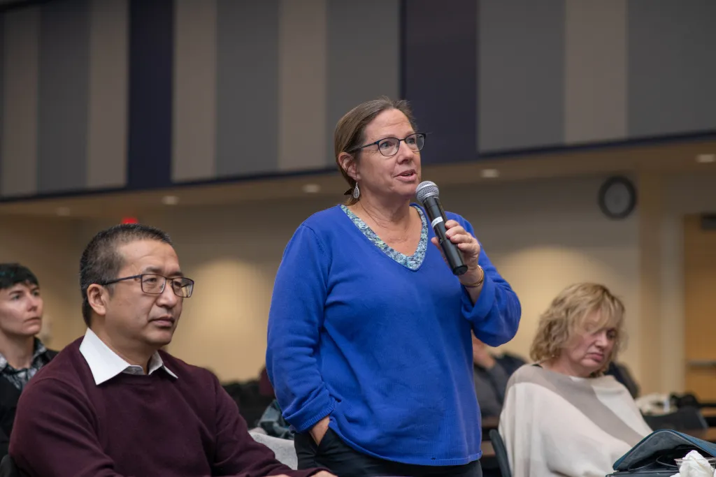 UNE professor Bethany Woodworth stands to ask the panel a question