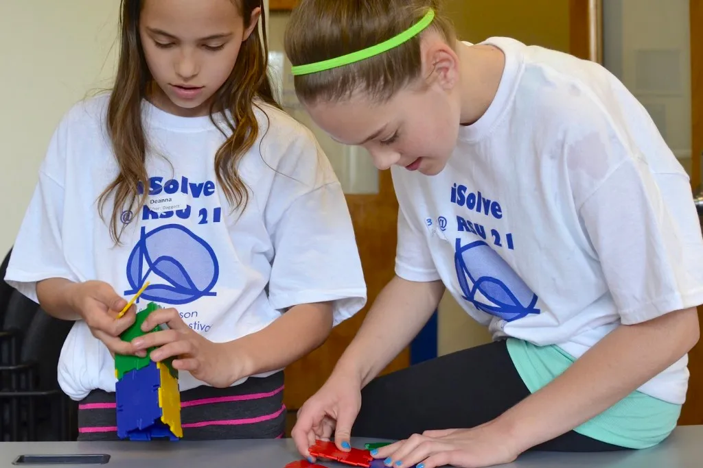 Two young girls putting puzzle pieces together