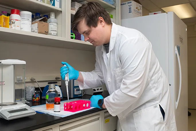 A student pipes a liquid into a container in a research lab