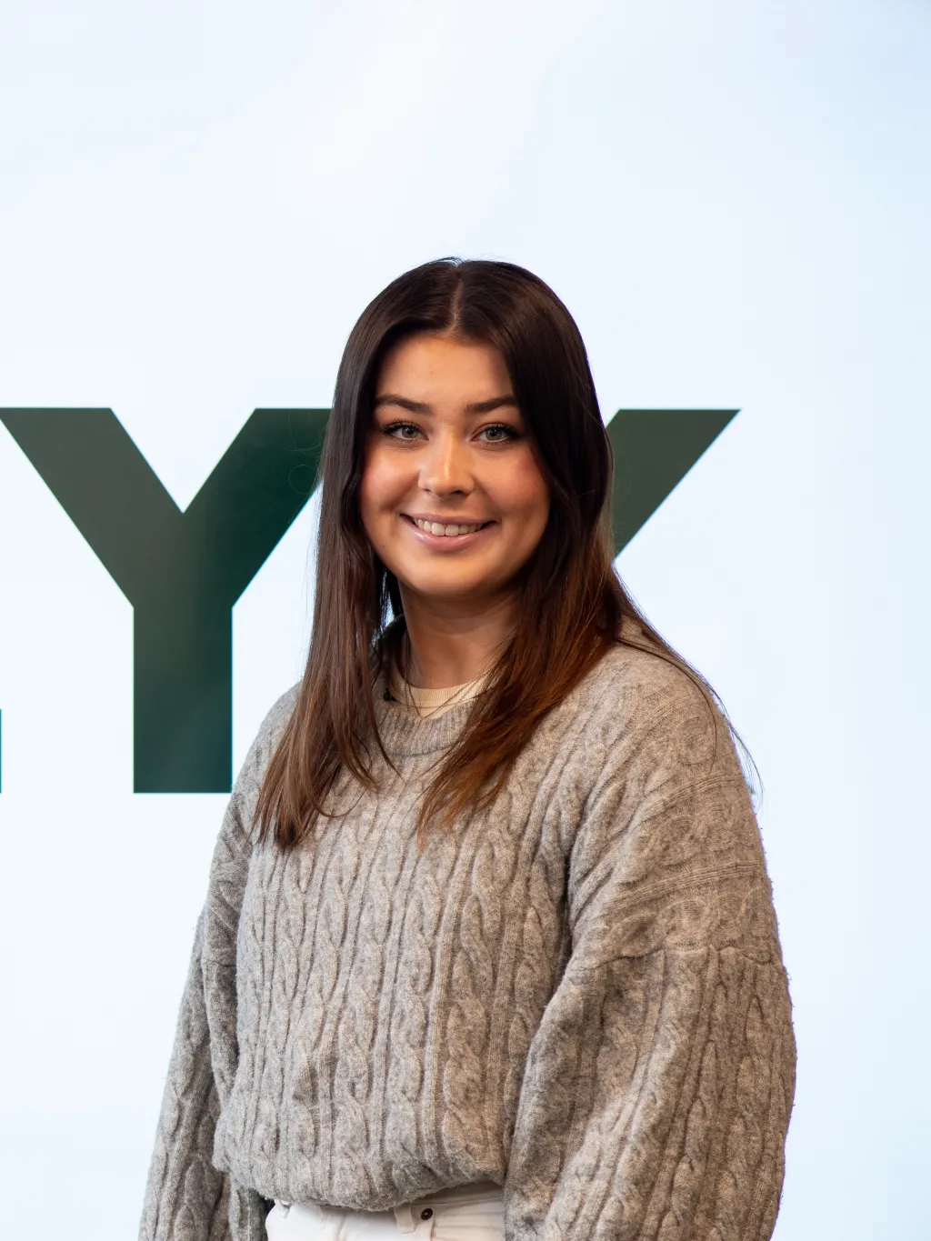 Abbie Anderson poses for a portrait. The name of her app, Clyk, is shown behind her