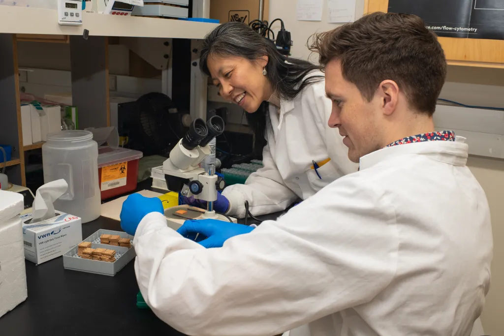 A professor works with a student to set up a microscope