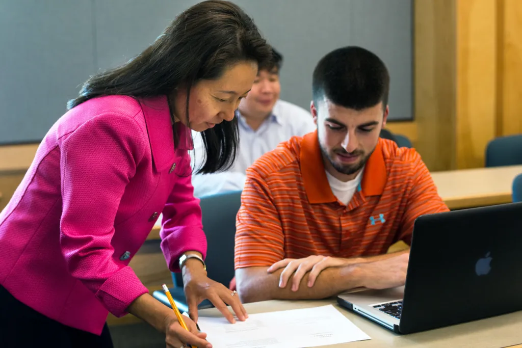 A faculty member looks over paperwork with a student