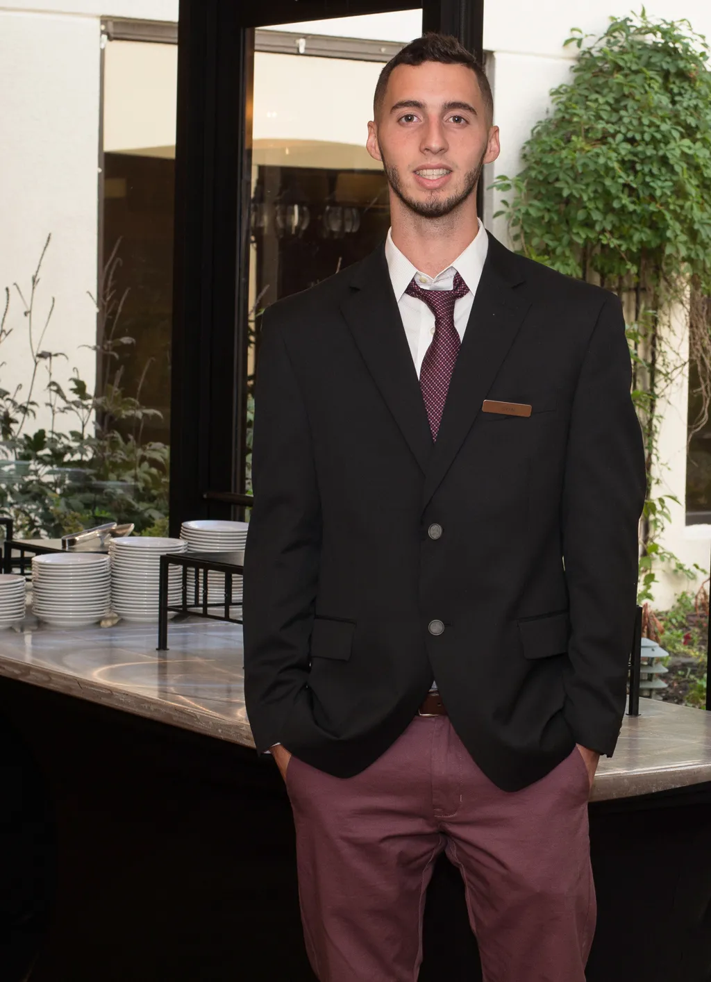 A U N E student stands in front of a table of plates and bowls at their hospitality internship