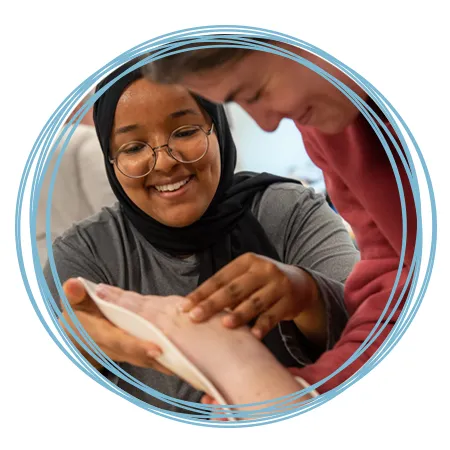 An O T student smiles as she practices placing a malleable splint on another student