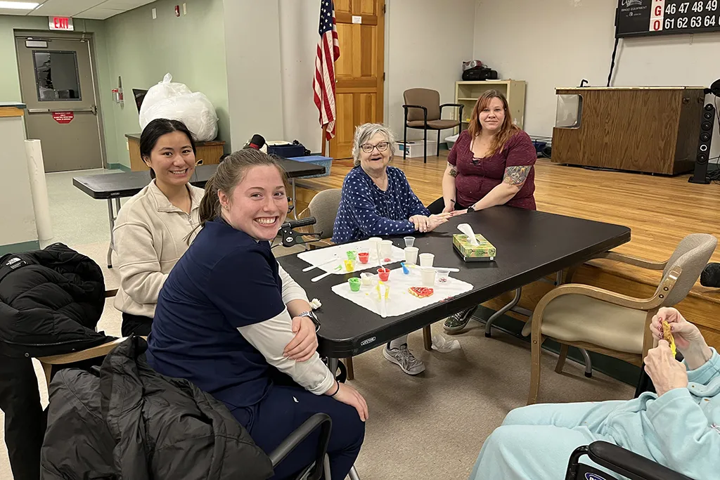 A group of students poses with residents of the Barron Center in Portland