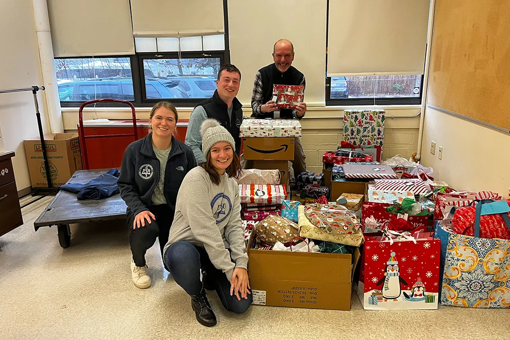 Students in UNE's Pediatrics Club and Sigma Sigma Phi pose in front of a collection of wrapped gifts for donation