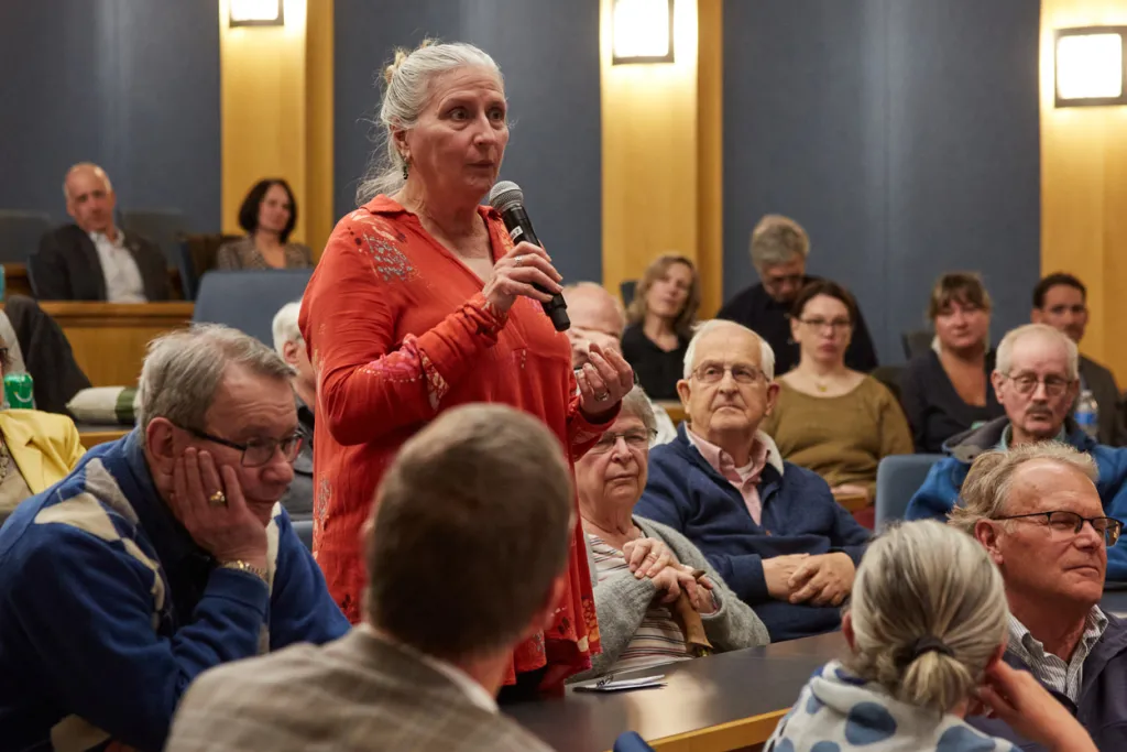 A community member asks a question from the audience of a C G H lecture