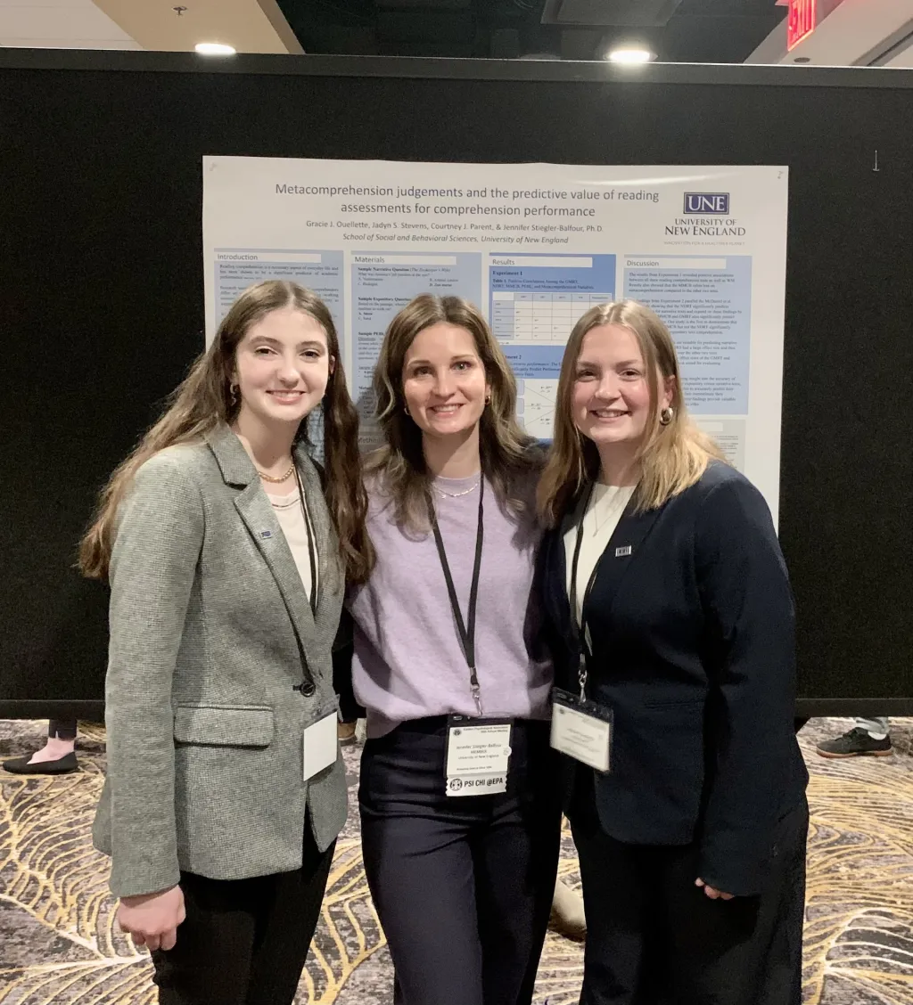 Three researchers pose in front of a poster