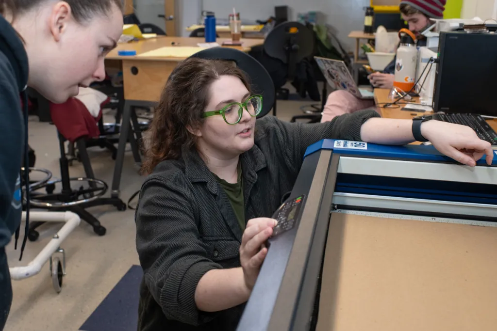 Two students talk over equipment in an assistive technology class