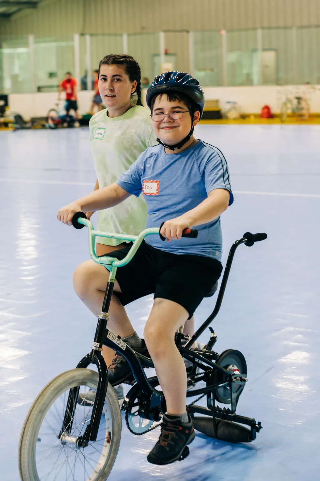 A young boy rides a bike inside a gymnasium