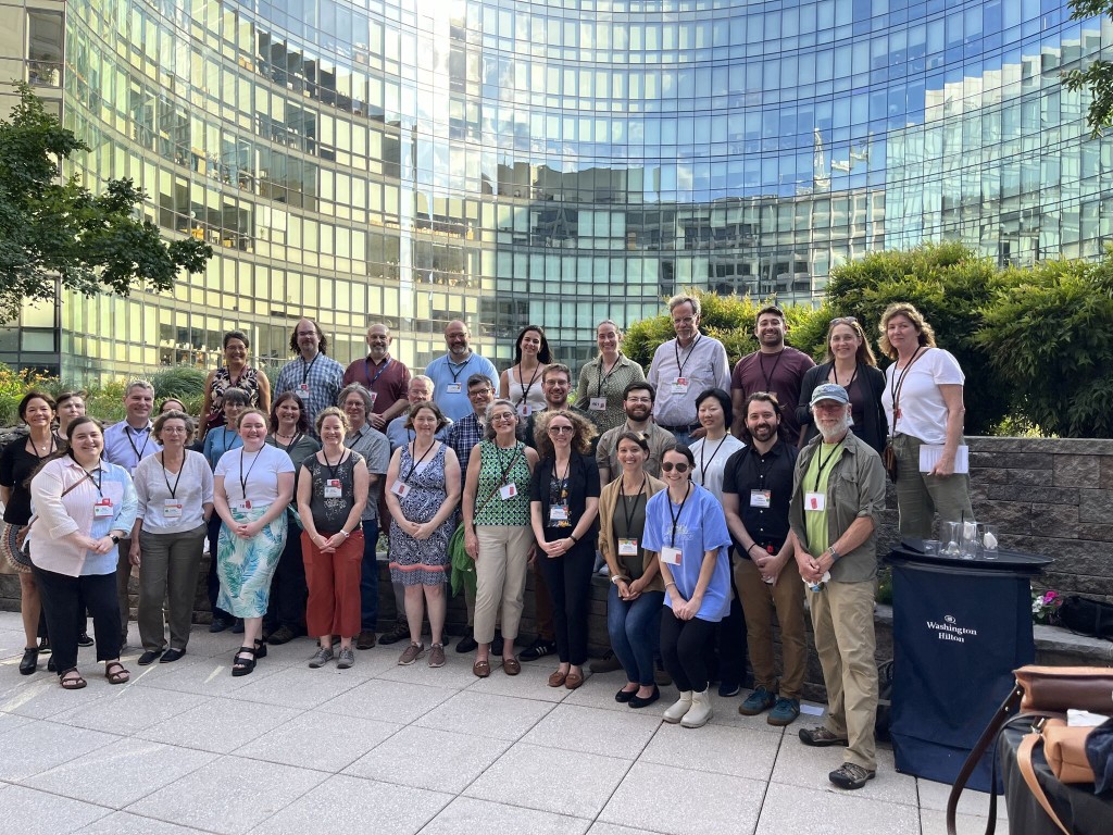A large group of researchers pose outside at a conference