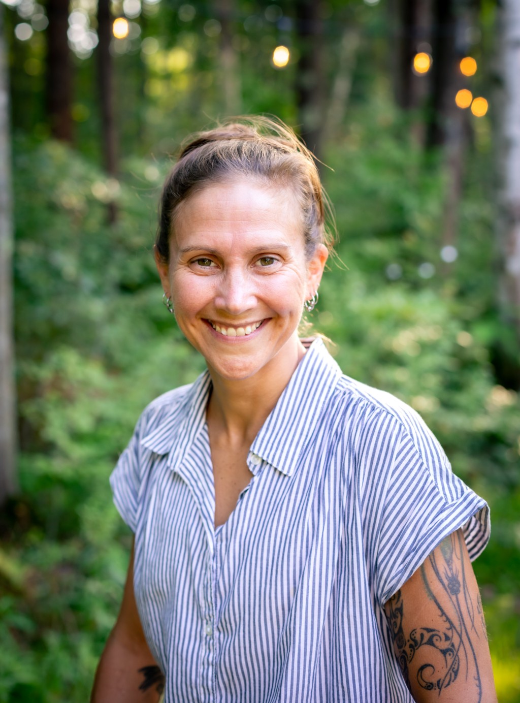 A woman smiles for a portrait against the woods