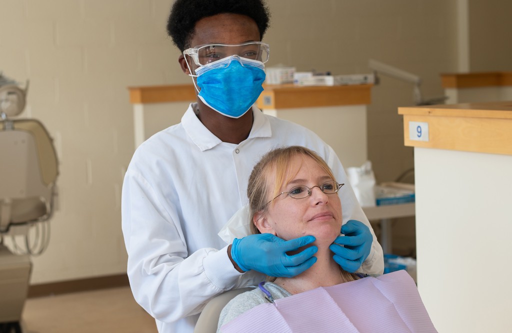 A U N E dental student does a palpation exam on a patient's jaw