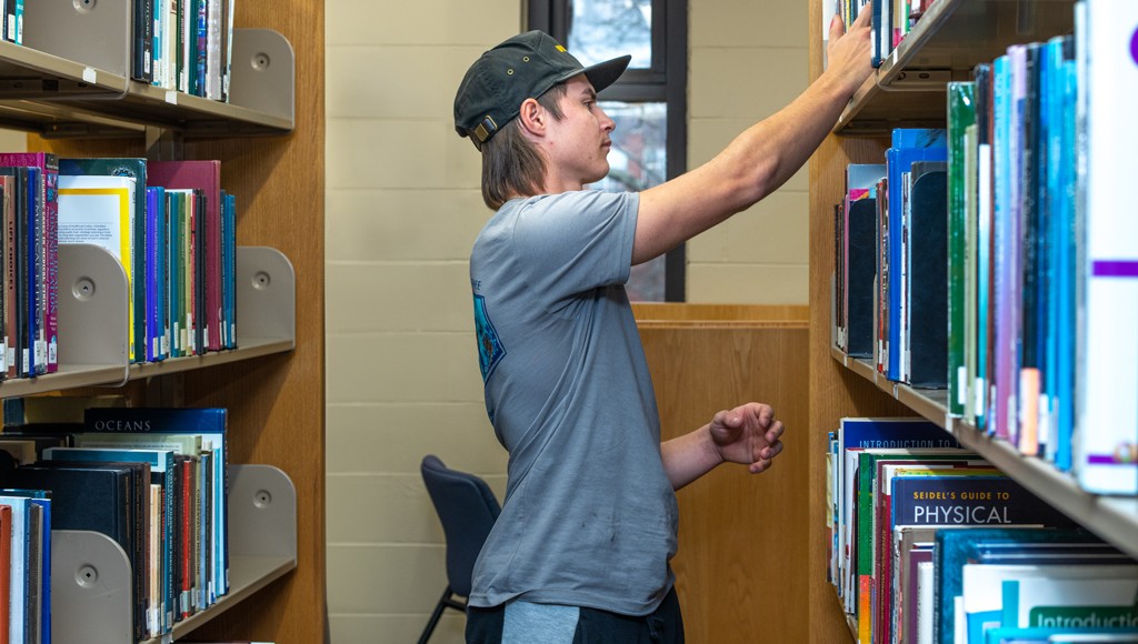 A student peruses the books in the library