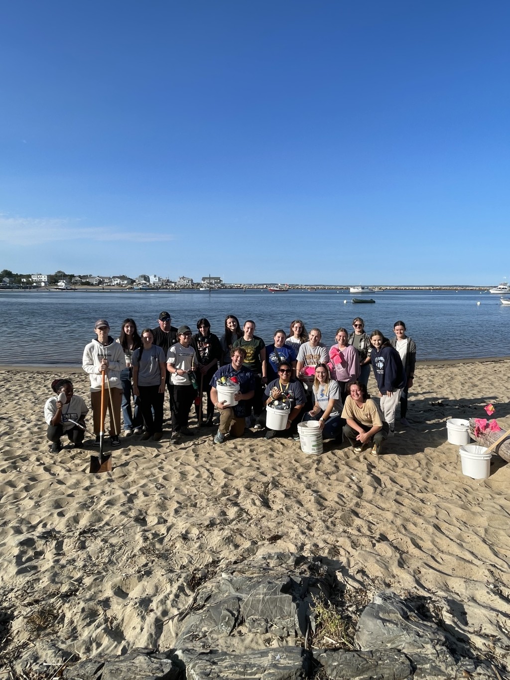 A group of students pose with buckets on Freddy Beach after cleaning up the sands