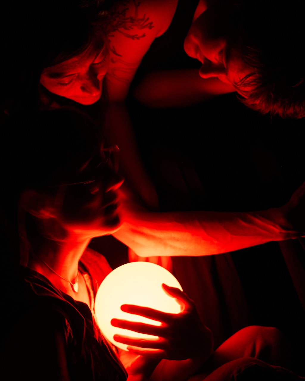 Two dancers stare into a red, glowing orb