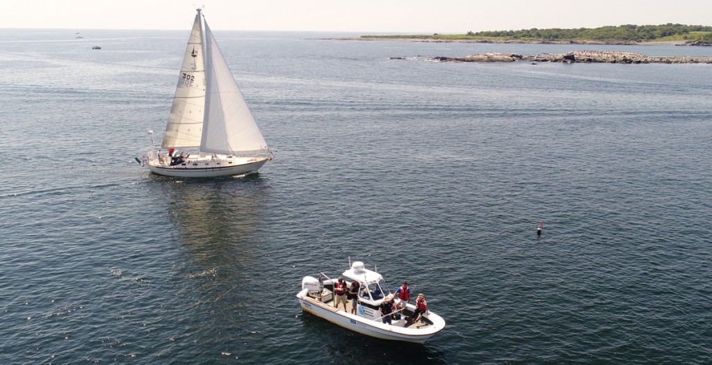 A sailboat and a small vessel move through the Atlantic Ocean off the coast of Maine