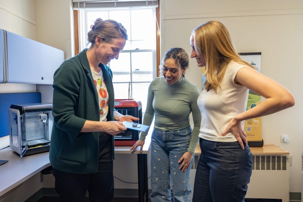 Two students and a professor examine a 3D printed medication container