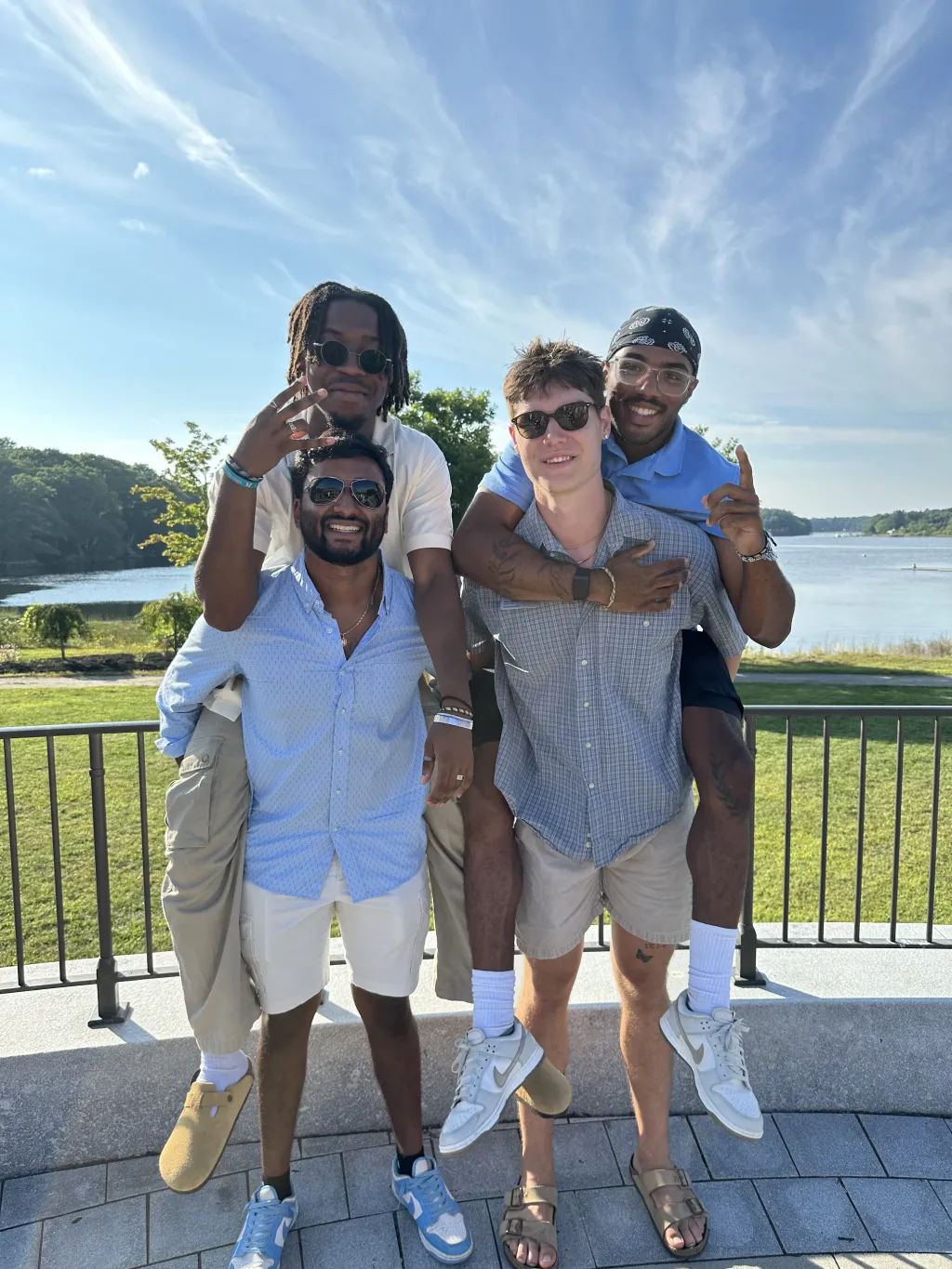 Four UNE students smile and pose for a photo on campus.