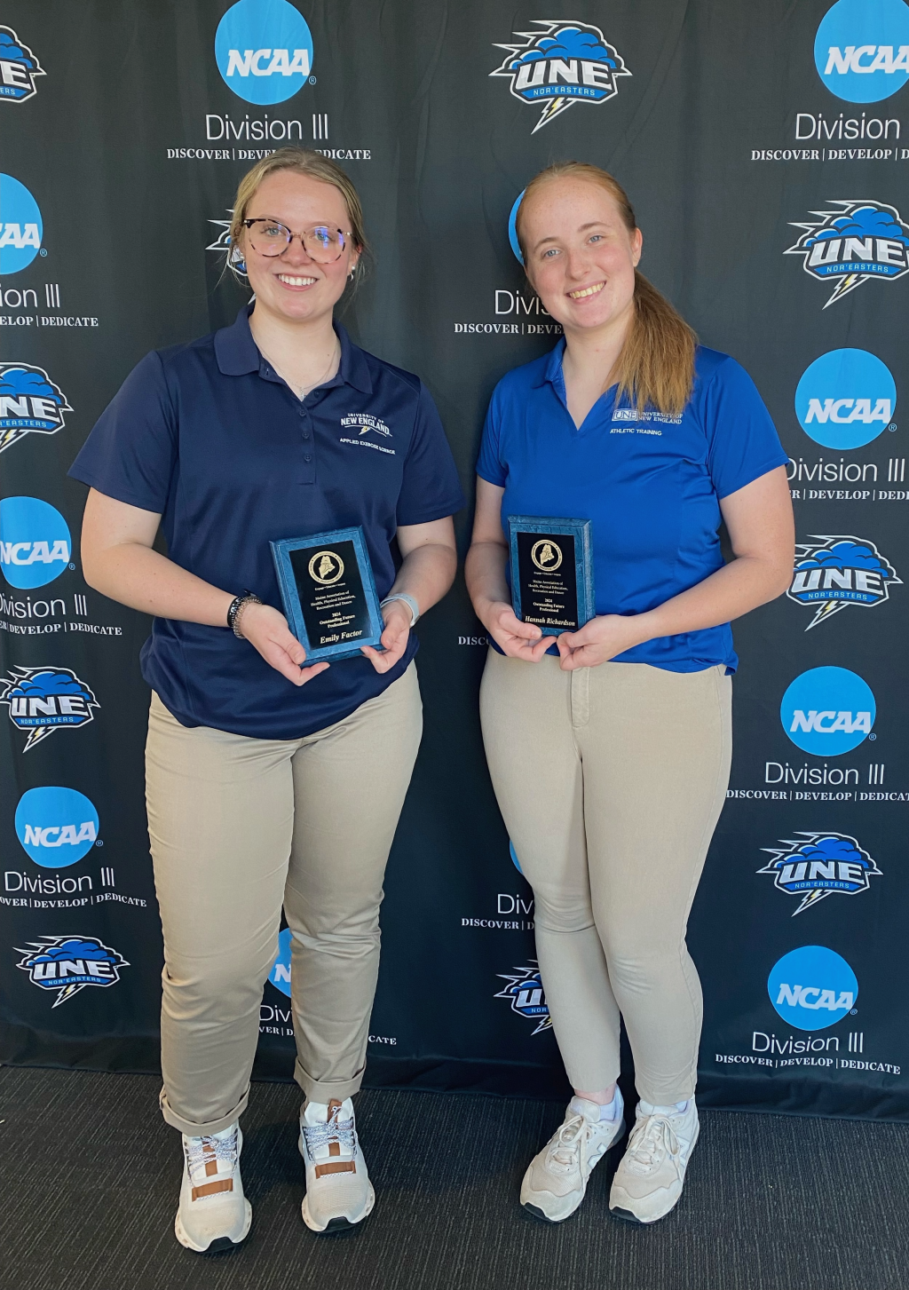 Two female students pose for a photo holding awards