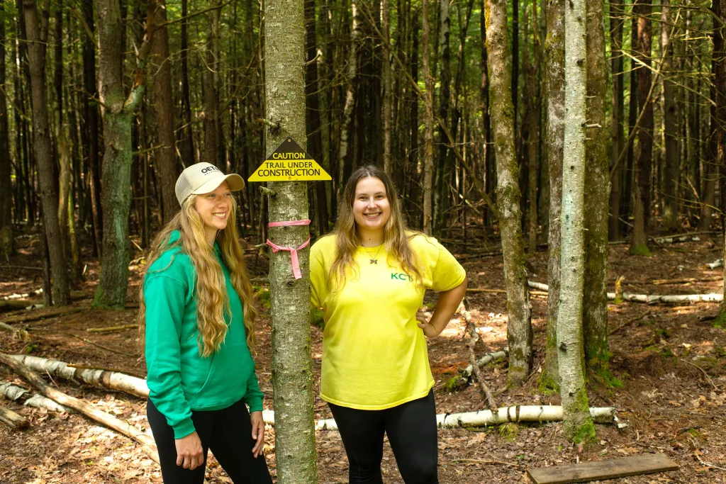 U N E students Julianne Lapiere and Mia Meister standing on a trail in Kennebunk