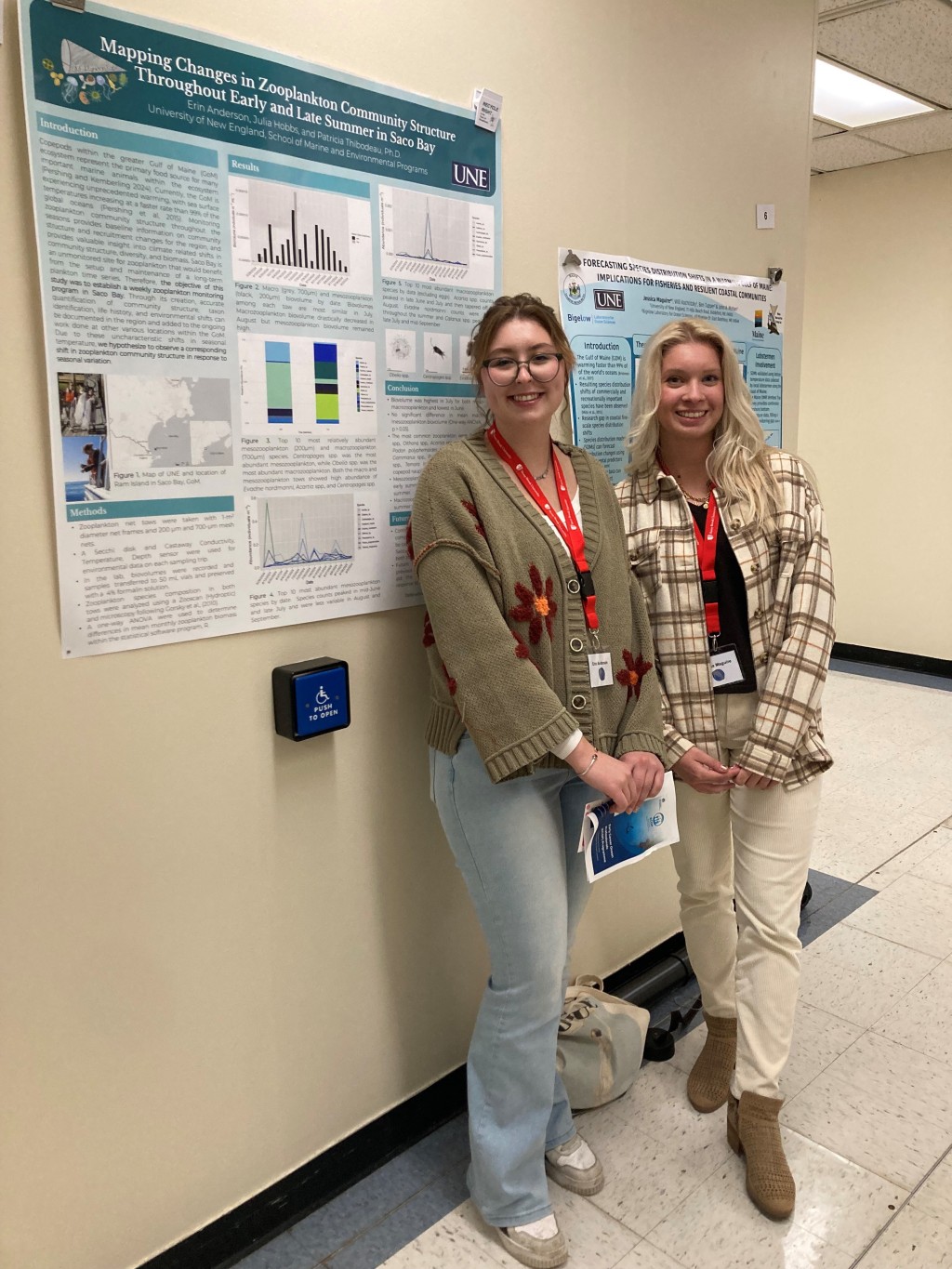 Two UNE students stand in front of a research poster