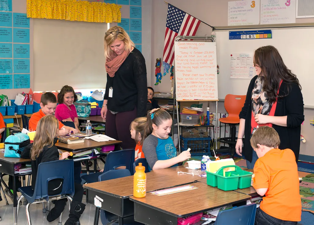 Two U N E education students teach children in an elementary school classroom