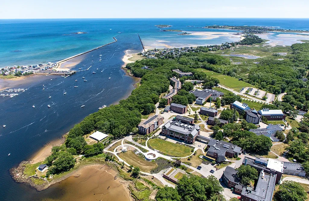 An aerial view of the U N E Biddeford Campus including the brick buildings, coastline, and ocean