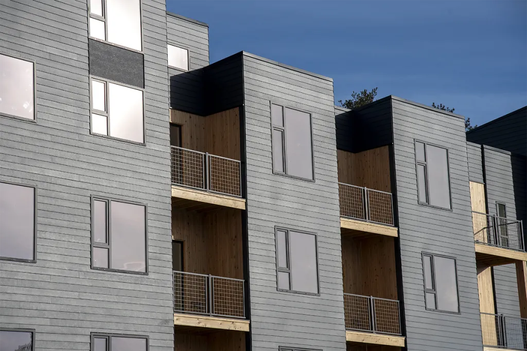 A close-up of the side of Seavey Terraces's grey siding, black-trim windows, and wood decks