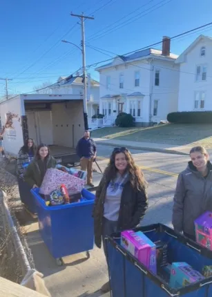 Students and volunteers load toys and gifts into a box truck