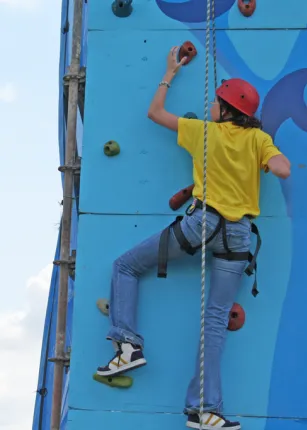 A student climbing an outdoor rock wall