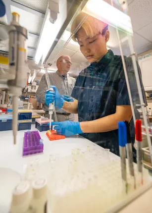 Ruby Motulsky pipetting DNA samples while Markus Frederich oversees the research