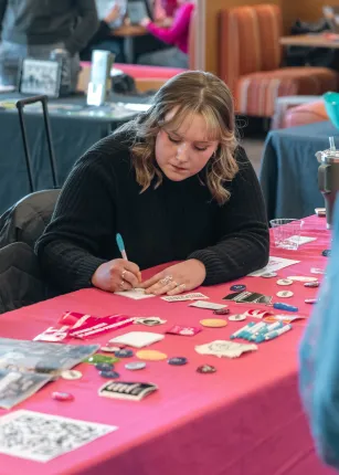 A volunteer stationed at a table during an organization fair in the Danielle N. Ripich Commons