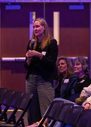 A woman stands to ask a question for panelists