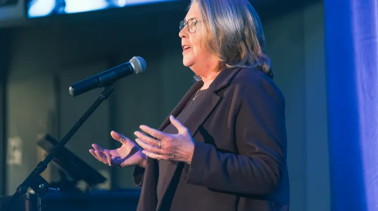 woman with hands open on stage