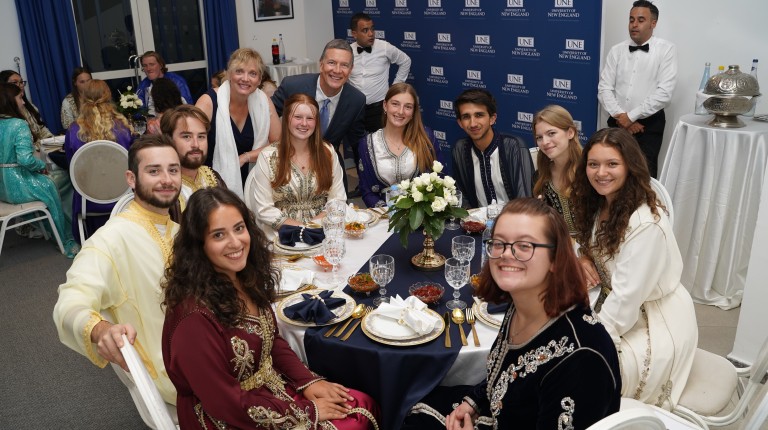 UNE students pose for a photo around a dinner table