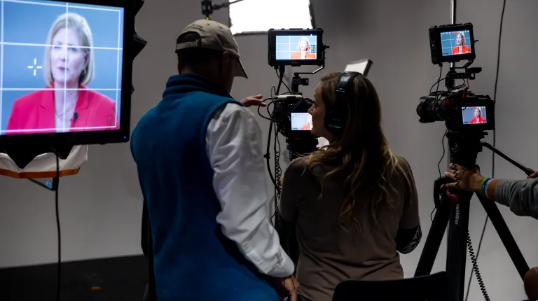 Stacia Deshishku is seen through a camera monitor as UNE students prepare equipment