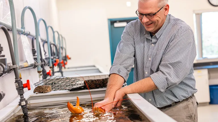 Markus Frederich holding Peaches in the water in Frederich's lab
