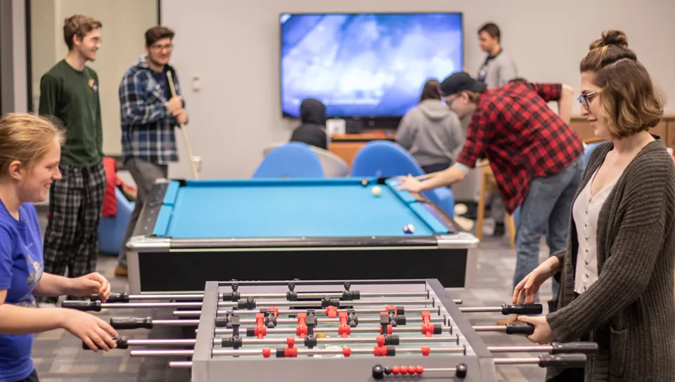 A group of students playing pool and foosball in the Commons